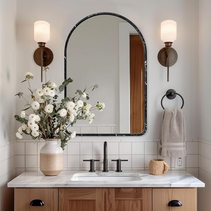 Arched marble mirror in a bathroom styled with nice interior design.